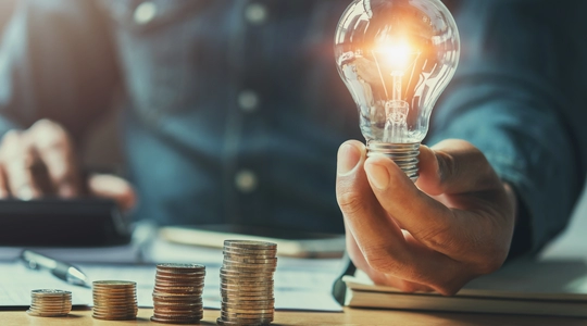business man hand holding lightbulb and using calculator