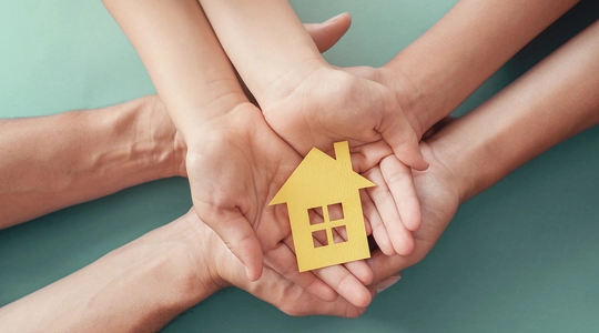 Adult and child hands holding paper house