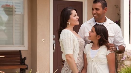 Mother, father, and daughter in front of house