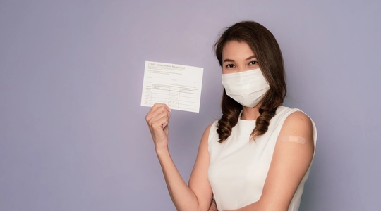 Woman wearing hygiene mask and carrying vaccination card