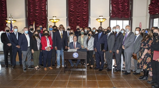 Eric Garcetti and Curren D Price Jr surrounded by City offcials at signing proclamation