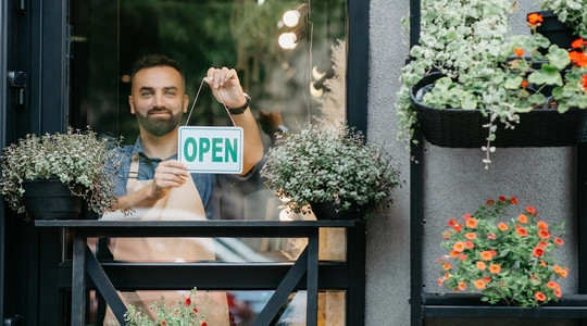 Man holding "Open" sign on store window