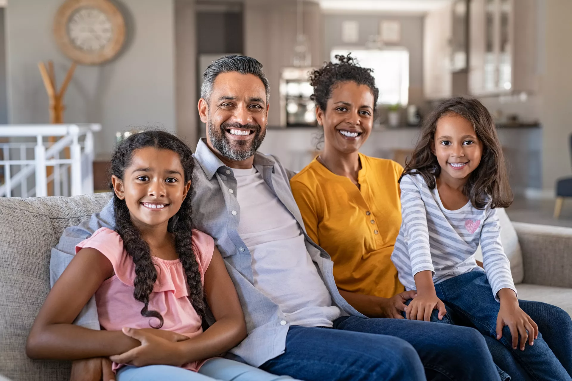 Portrait of cheerful ethnic family at home sitting on sofa