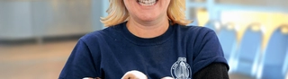Adult woman in a blue and black shirt holding 3 puppies