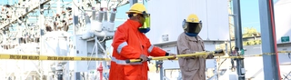 Two people in yellow hard hats holding a yellow tool