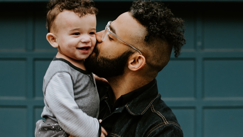 father kissing baby son on cheek