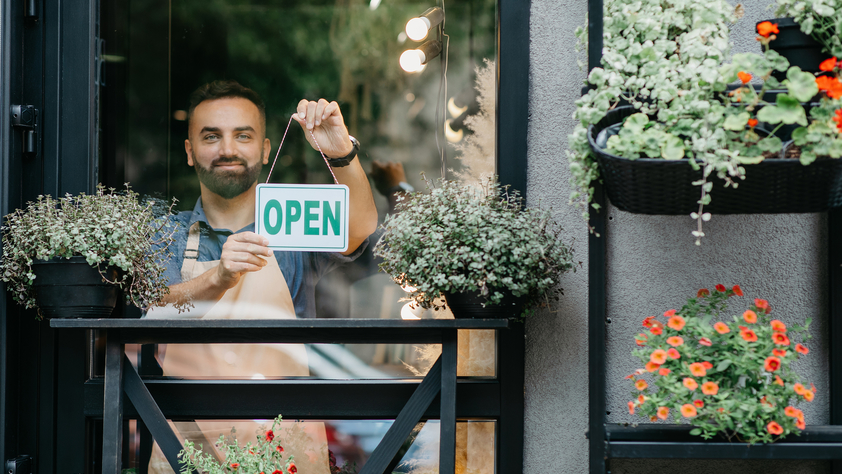 Man holding "Open" sign on store window